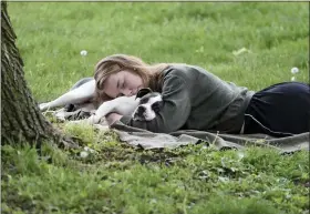  ?? PAM PANCHAK — PITTSBURGH POST-GAZETTE VIA AP FILE ?? A woman and her dog nap between rain showers at Schenley Park on May 4, 2021, in Pittsburgh. A Gallup survey, released Monday, says that a majority of Americans say they would feel better if they could have more sleep.