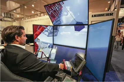  ?? Steve Gonzales / Houston Chronicle ?? Alek Kolin, a technical adviser at Liebherr, demonstrat­es a virtual reality crane at the Offshore Technology Conference.