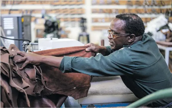  ?? Picture: AFP ?? HARD AT WORK. An employee of Courteney Boot selects leather that will be used to make shoes at the Bulawayo factory last month. The company exports mostly to the US, Europe, Britain and South Africa.