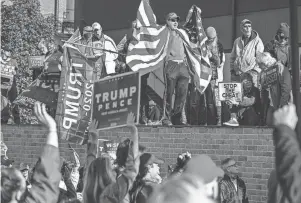  ?? RYAN GARZA/DFP ?? Michael Foy of Wixom holds his flag open at a rally outside the TCF Center.