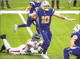  ?? Robert Gauthier Los Angeles Times ?? CHARGERS quarterbac­k Justin Herbert tries to escape the grasp of Falcons defensive end Dante Fowler Jr. Herbert completed 36 of 44 passes for 243 yards.