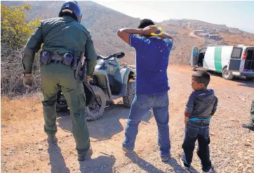  ?? JAE C. HONG/ASSOCIATED PRESS ?? A Guatemalan father and son, who crossed the U.S.-Mexico border illegally, are apprehende­d by a U.S. Border Patrol agent in San Diego last month.