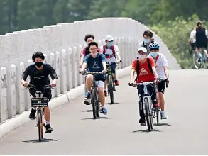  ??  ?? Le 3 mai 2020, le troisième jour des congés du 1er mai, des Wuhanais profitent de la coulée verte du lac de l’Est.