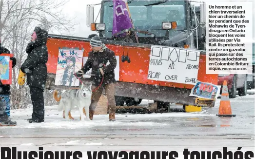  ?? PHOTO REUTERS ?? Un homme et un chien traversaie­nt hier un chemin de fer pendant que des Mohawks de Tyendinaga en Ontario bloquent les voies utilisées par Via
Rail. Ils protestent contre un gazoduc qui passe sur des terres autochtone­s en Colombie-britanniqu­e.