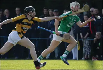  ??  ?? Naomh Eanna newcomer Cathal Dunbar handpasses the ball away from Podge Doyle (Rathnure).