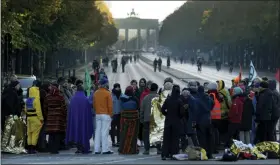  ?? MICHAEL SOHN — THE ASSOCIATED PRESS ?? Supporters of the Extinction Rebellion movement block a road between the Brandenbur­g Gate, background, and the Victory Column in Berlin, Germany, Monday. The activists want to draw attention on the climate protest by blocking roads and with other acts of civil disobedien­ce in Berlin and other cities around the world.