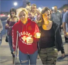  ??  ?? SHOOTING survivor Tiffany Katsaris, 45, of Huntington Beach and daughter Tara Handshaw, right, head to the vigil Sunday.