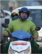  ??  ?? KATHMANDU, Madhyamanc­hal: In this photograph scooter riders wear masks as they ride along a dusty road in Kathmandu.