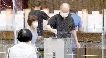  ?? — AFP file ?? A man casts his vote for the Tokyo gubernator­ial election behind a sheet of plastic as a precaution at a polling station in Shinjuku area in Tokyo. – AFP photo