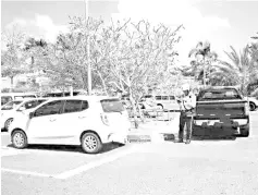  ??  ?? Traffic police issuing a summons to a car parked illegally at Hospital Duchess of Kent in Sandakan.