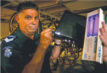  ?? Picture: PAT SCALA ?? ON TRIAL: Leading Senior Constable Steve Gambetta inspects items with a UV torch.