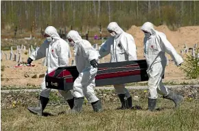  ?? AP ?? Grave diggers wearing personal protective suits carry a coffin while burying a Covid-19 victim in the special purpose for coronaviru­s victims section of a cemetery in Kolpino, outside St Petersburg.