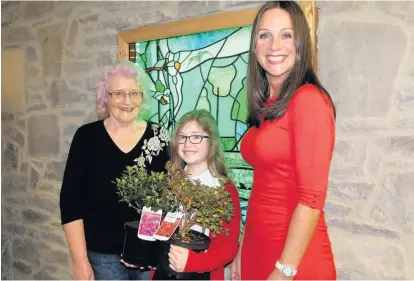  ??  ?? Bee-lieve Rose Paterson from ACB handing over the plants to Holly Archer and Miss Muir from Sandford Primary