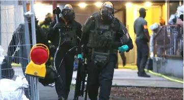  ?? — AFP photo ?? Police officers, including special forces wearing protective suits walk out of a building in Cologne, where German police have arrested a Tunisian man after discoverin­g ‘toxic substances’ at his flat.