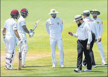  ?? AFP ?? Umpire Aleem Dar checks the ball as Sri Lanka captain Dinesh Chandimal (C) looks on.