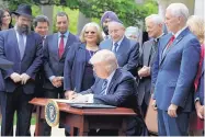  ?? EVAN VUCCI/ASSOCIATED PRESS ?? President Donald Trump signs an executive order in the Rose Garden of the White House in Washington on Thursday limiting IRS action over church political activity.