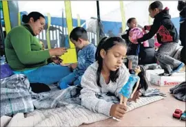  ?? Gary Coronado Los Angeles Times ?? SUANY RODRIGUEZ, 6, plays with a doll at a camp in Tijuana. Her mother, left, fled Honduras with her kids after the father was killed and she was threatened.