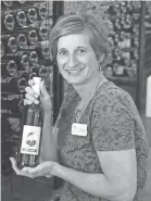 ??  ?? Carrie Lautenbach-Viste holds a bottle of cherry wine at Lautenbach Orchard Country.
