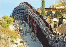  ?? AP ?? US Army troops install additional concertina wire on the border fence on a hillside above Nelson Street in downtown Nogales, Arizona. Mexico is visible at right.