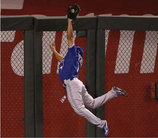  ?? RICK MADONIK/TORONTO STAR ?? Jays outfielder Ben Revere makes an outstandin­g catch at the wall in the seventh inning of Friday night’s Game 6. For game coverage, visit thestar.com/sports.