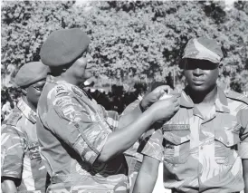  ??  ?? The Chief of Staff Major-General Trust Mugova confers a rank of Lance Corporal to Nomore Marambakuy­ana of 13 Reserve Force Battalion during a passout parade at Mbalabala last week