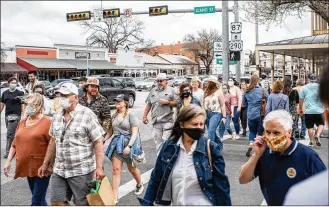  ??  ?? Residents and visitors with and without masks on Main Street in Fredericks­burg, Texas, on March 13. Many workers say that their stores do not enforce the requiremen­t, and that if they do approach customers, they risk verbal or physical altercatio­ns.