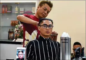  ??  ?? Le Tuan Duong propose des coupes de cheveux à la Kim Jong-un gratuites.