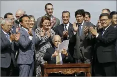  ??  ?? Gov. Jerry Brown holds up a number of bills he signed to help address housing needs as a group of elected officials and housing advocates applaud, Friday, in San Francisco. AP PHOTO/ERIC RISBERG