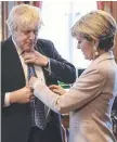  ??  ?? Boris Johnson has his tie straighten­ed by Julie Bishop.