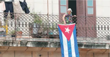  ?? EFE ?? Una mujer ya entrada en años coloca una bandera cubana en apoyo a las protestas.