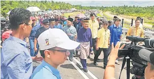  ??  ?? BOLEH DILALUI: Talib (tengah) sambil diiringi Cassidy dan Lau bersama tetamu lain berjalan ke Jambatan Kuala Tatau bagi menyempurn­akan acara simbolik izin lalu awam jambatan terbabit.