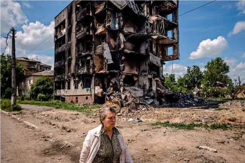  ?? IN THE TOWN OF BORODYANKA, UKRAINE, ON WEDNESDAY. — afp ?? A woman walks past a destroyed apartment building