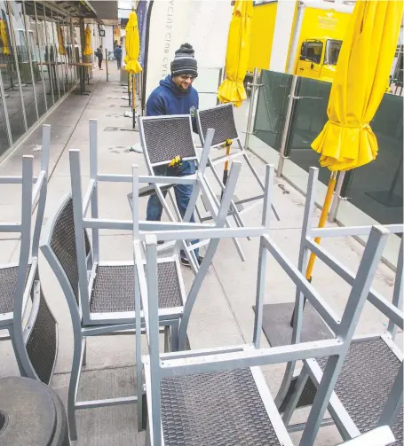  ?? GAVIN YOUNG ?? Alberto Torres with Calgary Profession­al Movers stocks chairs in the outdoor patio at the Cactus Club in the downtown area on Monday. Alberta is potentiall­y set to reopen restaurant­s for dine-in seating with restrictio­ns, this week.