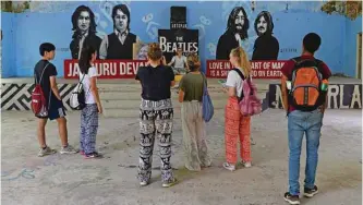  ??  ?? Tourists taking pictures of a mural at the now-derelict ashram visited by the Beatles 50 years ago, in Rishikesh in northern India.