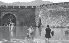  ?? WENG XINYANG / XINHUA ?? Right: Residents wade through floodwater in front of the city wall in Linhai.