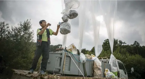  ?? JEAN CHUNG PHOTOS/THE NEW YORK TIMES ?? Lee Min-bok, a North Korean defector, prepares to release balloons with bags of leaflets to North Korea near the Demilitari­zed Zone in Pocheon, South Korea.