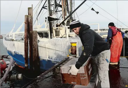  ?? DANA JENSEN/THE DAY ?? Alex Perez stacks boxes of fish on a pallet Tuesday while he and others unload fish from the ice-covered vessel Mystic Way at New London Seafood Distributo­rs on the Thames River in New London. The cold is expected to continue for several more days.