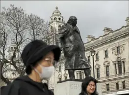  ?? Matt Dunham/Associated Press ?? A masked tourist stands next to the statue of former British Prime Minister Winston Churchill in Parliament Square in London in March.