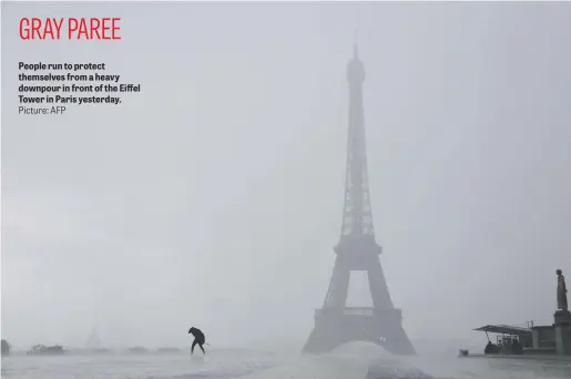  ?? Picture: AFP ?? People run to protect themselves from a heavy downpour in front of the Eiffel Tower in Paris yesterday.