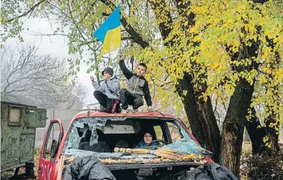  ?? AFP ?? Un grup de nens jugant amb una bandera en un punt de control a l’entrada de Kherson