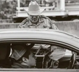  ?? Godofredo A. Vásquez / Staff photograph­er ?? A Texas Highway Patrol trooper talks to motorists at the Texas Travel Informatio­n Center parking lot on March 30 in Orange.