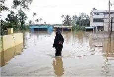  ?? — AFP ?? A woman walks in floodwater­s on the outskirts of Kushalnaga­r in Kodagu district of Karnataka.