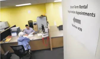  ?? Carlos Avila Gonzalez / The Chronicle ?? A sign points to the desk where Senior Analyst Omar Masry helps Marcy Lipton with her paperwork for hosting guests in her home at the Office of Short Term Rentals in San Francisco.