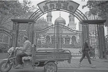  ??  ?? People walking past a mosque in Urumqi, the regional capital of Xinjiang.