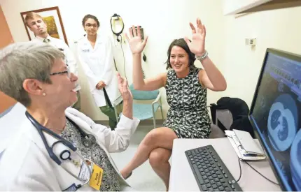  ?? MIKE DE SISTI / MILWAUKEE JOURNAL SENTINEL ?? Melanie Thwing (right) and Pat Quinn-Casper, a nurse practition­er, celebrate a lighter moment while looking at Thwing’s CT scans as medical students look on.