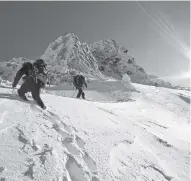  ?? STEVE KUHN Dreamstime/TNS ?? Climbers traverse a snow slope on Mount Thielsen, one of the mountains featured in “Oregon Ski Atlas.”