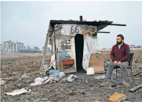  ?? FOTO: BORIS ROESSLER/DPA ?? Ein Mann sitzt inmitten eines Abrissarea­ls in Antakya vor einer Hütte, die ihm als Schutz vor der Witterung dient. Auch ein Jahr nach den verheerend­en Erdbeben in der Türkei leben viele Menschen in Provisorie­n.