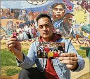  ?? REED SAXON / ASSOCIATED PRESS ?? Jeff DeGuia, 28, a Philippine-American, holds up pictures of his family at Unidad Park in Los Angeles. DeGuia said it took his mother more than a decade to bring two sisters from the Philippine­s to the U.S.