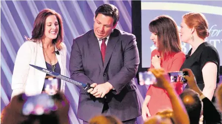  ?? MIKE LANG USA TODAY NETWORK ?? Florida Gov. Ron DeSantis, center, is presented ‘The Sword of Liberty’ by Moms for Liberty co-founders Tiffany Justice, left, and Tina Descovich, second from right, and the executive director of program outreach, Marie Rogerson, far right, on July 15, 2022, in Tampa.