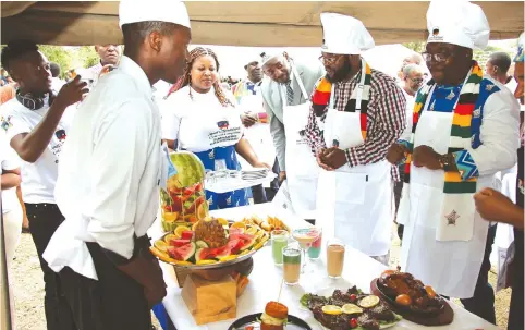  ?? — Picture: Tinai Nyadzayo ?? Tourism and Hospitalit­y Industry Deputy Minister Tongai Mnangagwa (right) and Minister of State for Manicaland Provincial Affairs and Devolution, Advocate Misheck Mugadza, inspect traditiona­l dishes prepared by Dylan Mumba of Mutare Polytechni­c during the Amai’s provincial traditiona­l cookout competitio­n at Mutare Teachers’ College on Wednesday. Manicaland will host this year’s national competitio­ns.